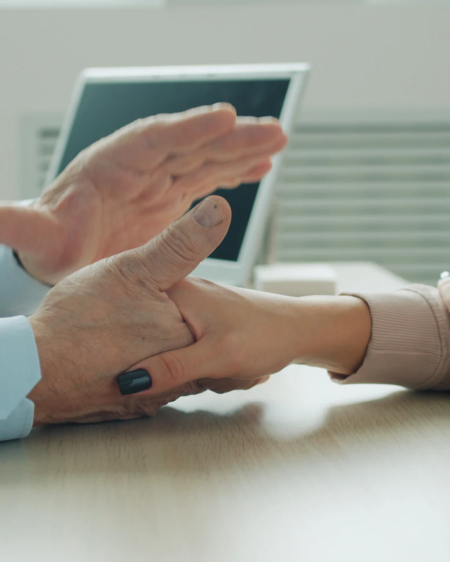 Manos del médico sosteniendo con calma la mano de una paciente durante la consulta