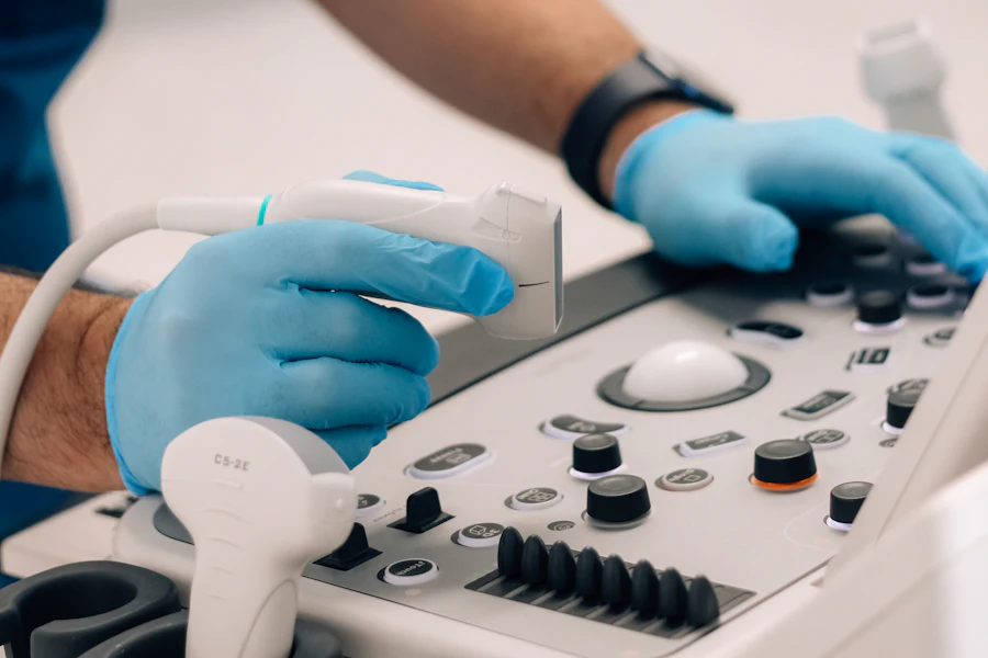 Profesional con guantes manejando el transductor y el panel de un ecógrafo